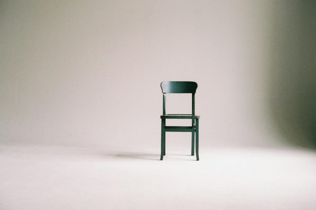 A single black chair in a minimalistic studio setting with a neutral backdrop.
